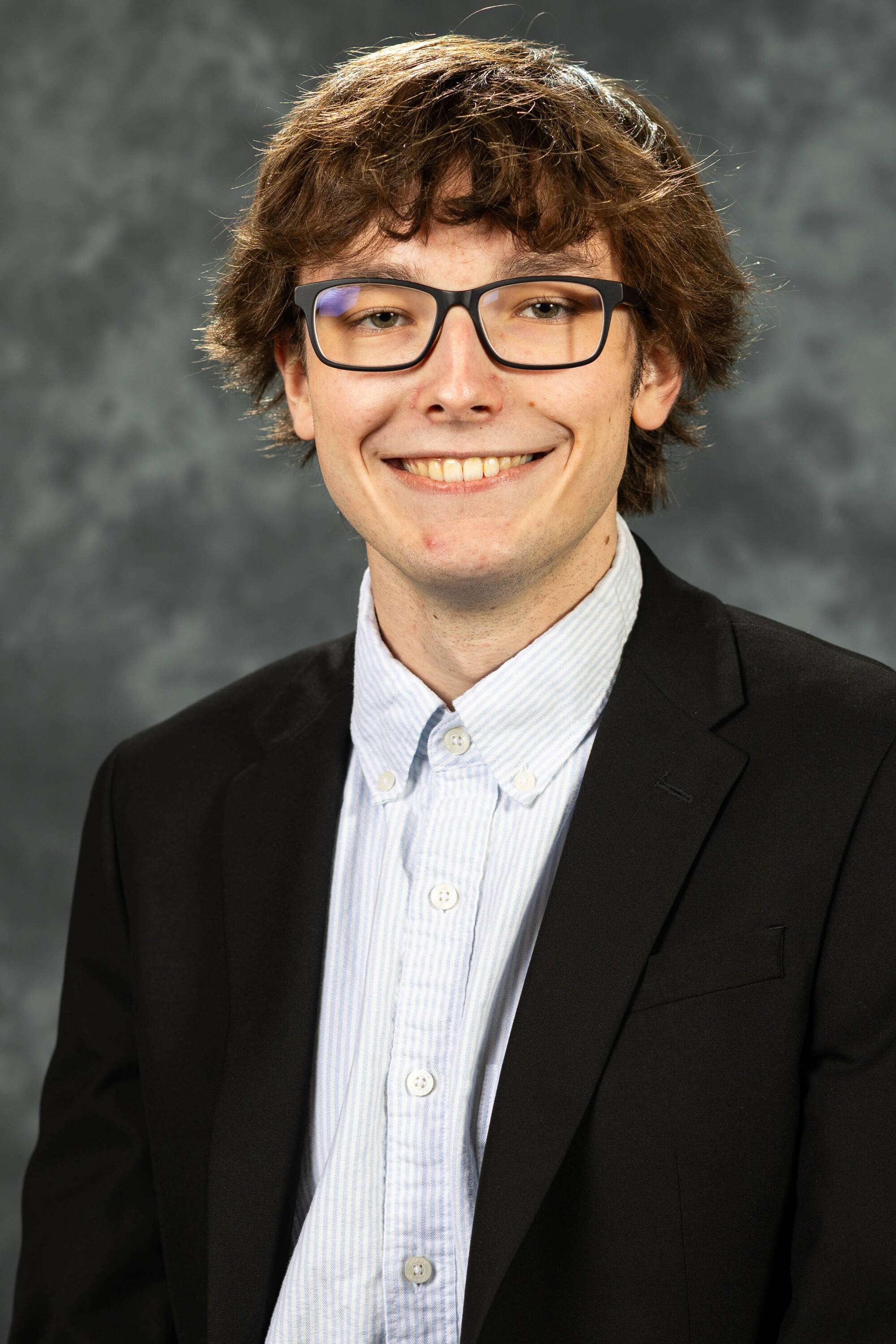 William Laurin smiling in a white button-up shirt and a black blazer.
